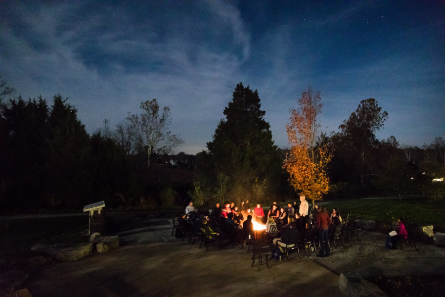 A group of people hang out around a bonfire at the National Conservation Training Center.