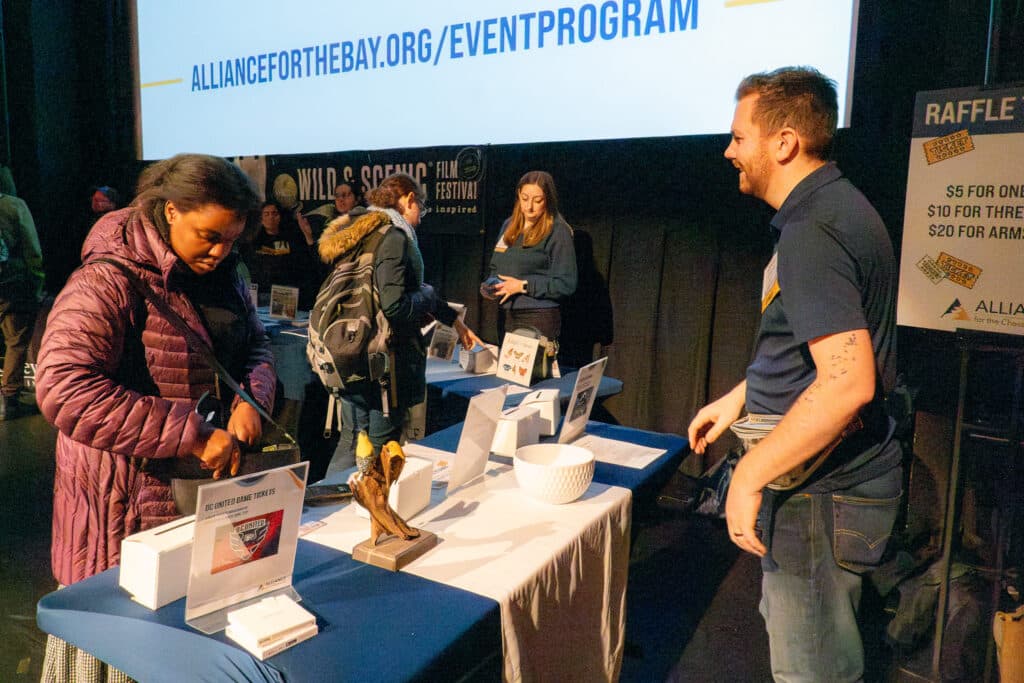 People exploring raffle items at a table during the WSFF DC event in 2025.