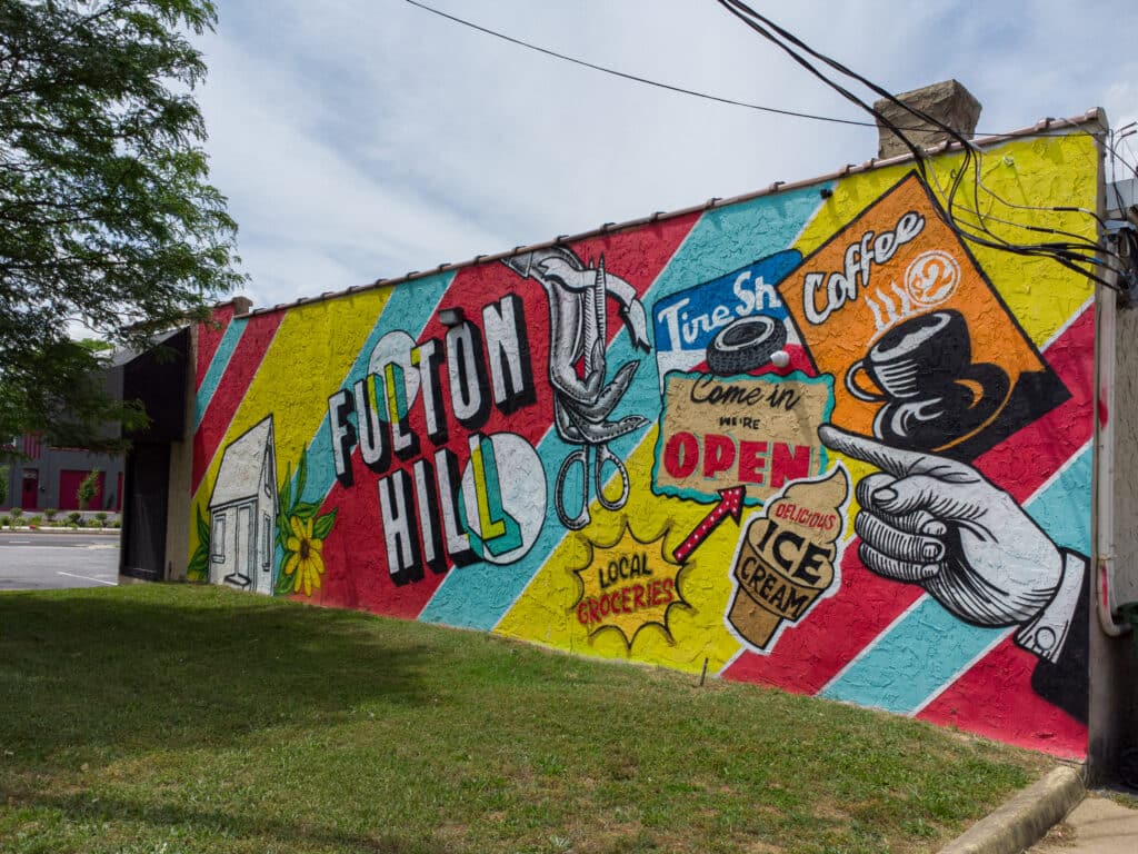 Fulton Hill mural with bright colors and old fashioned business signage.