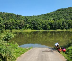 A person moving kayaks at a boat ramp, under a clear blue sky..