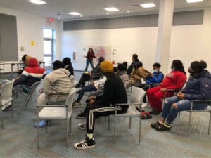 A room of people listening to a person speaking