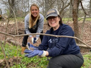 Two people posing while holding a garter snake.