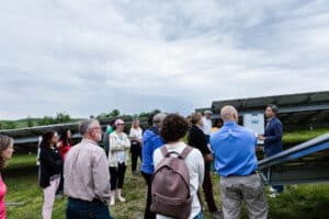 A group of people standing near solar panels in a field.