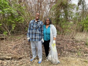 Two people smiling and holding trash bags.