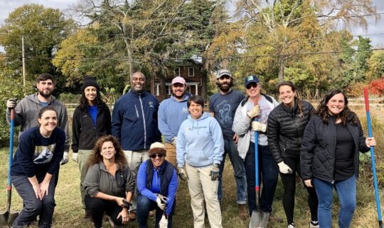 A group of people posing and smiling with gardening equipment.