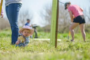 A baby sitting next to a newly planted tree