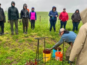 A group of volunteers watching a planting demonstration