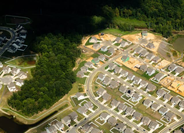 An aerial view of a neighborhood of houses combined with forest