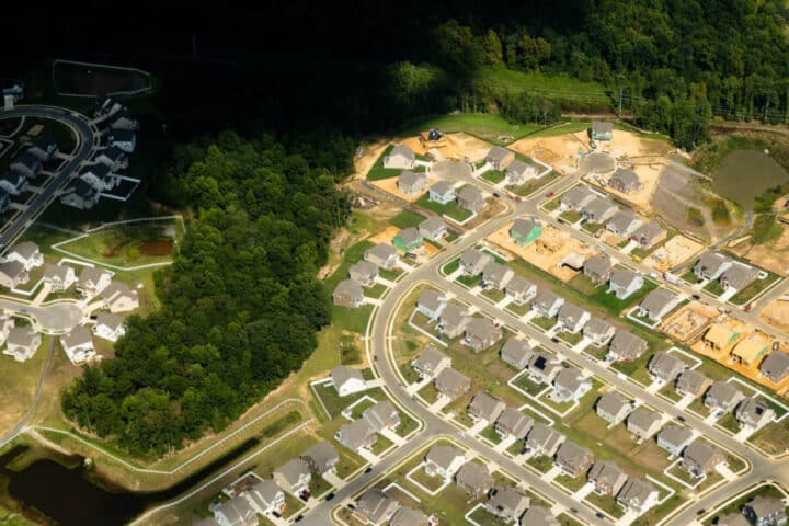 An aerial view of a neighborhood of houses combined with forest