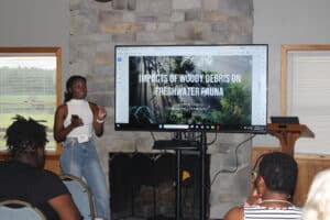 A person giving a presentation, with the screen reading "Impacts of Woody Debris on Freshwater Fauna"