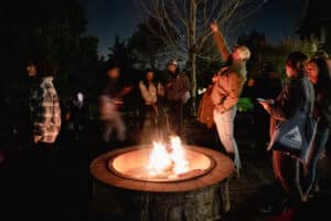 People gathered around a fire pit, looking up at the night sky