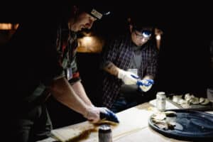 Two people preparing oysters with head lamps at night