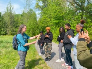 A group of people gathered around a speaker holding a cattail plant.