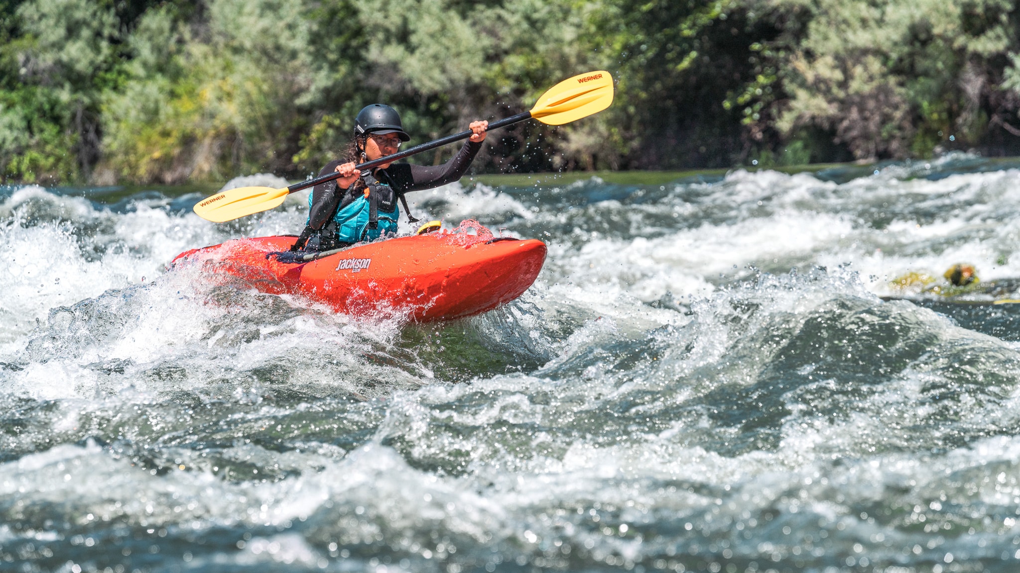 A person in a red kayak paddling rapids