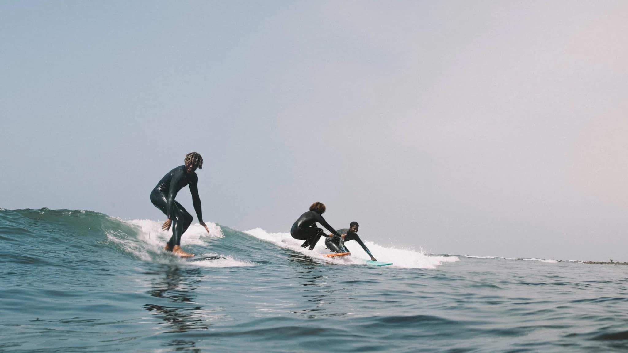 Three people smiling and surfing