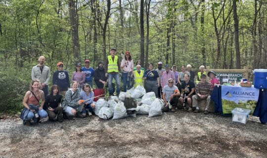 A group of volunteers pose behind several bags of trash on a trail at Crooked Branch Ravine Park.