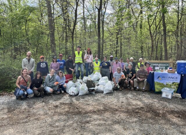 A group of volunteers pose behind several bags of trash on a trail at Crooked Branch Ravine Park.