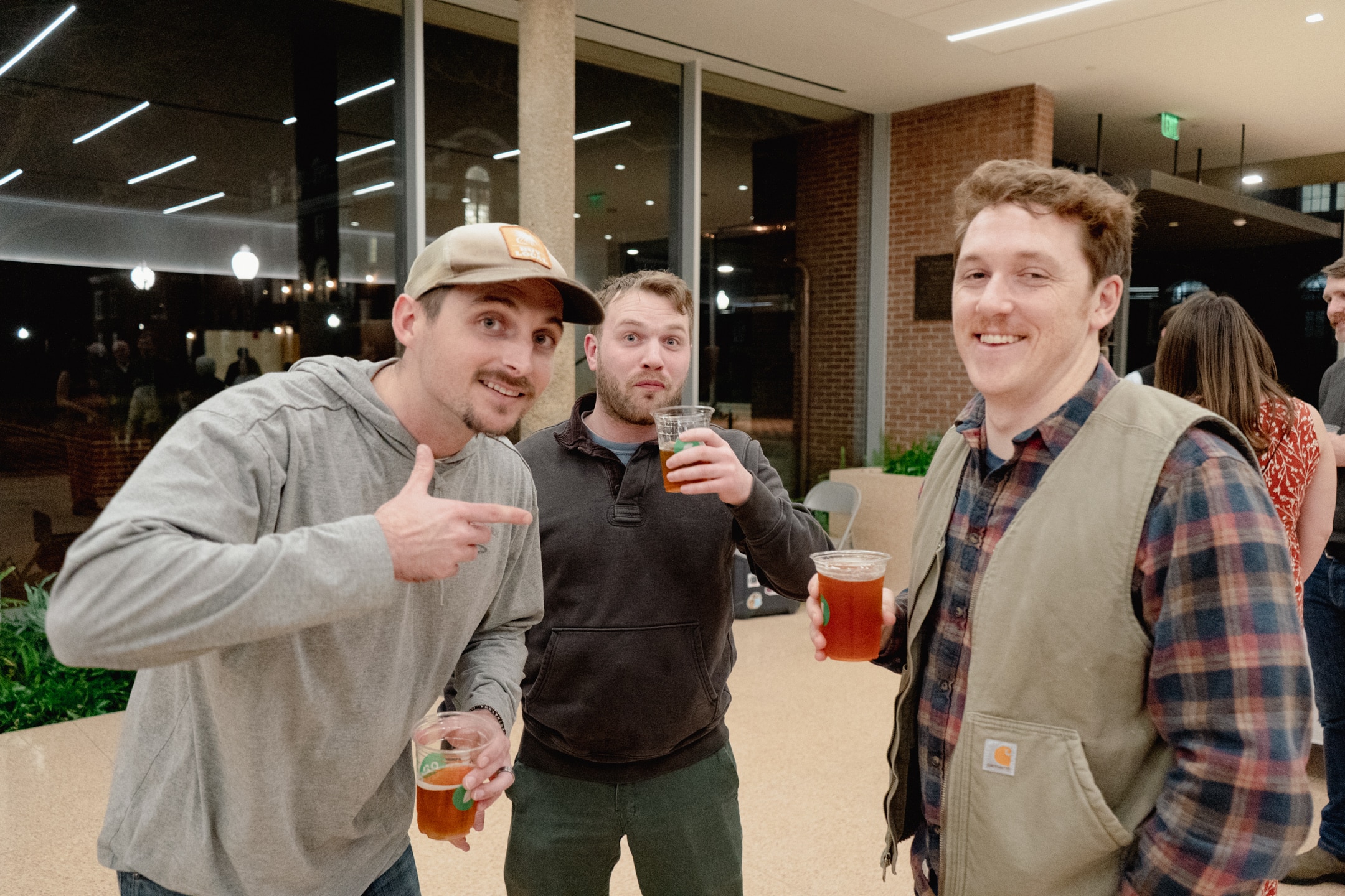 Three people smiling and holding drinks