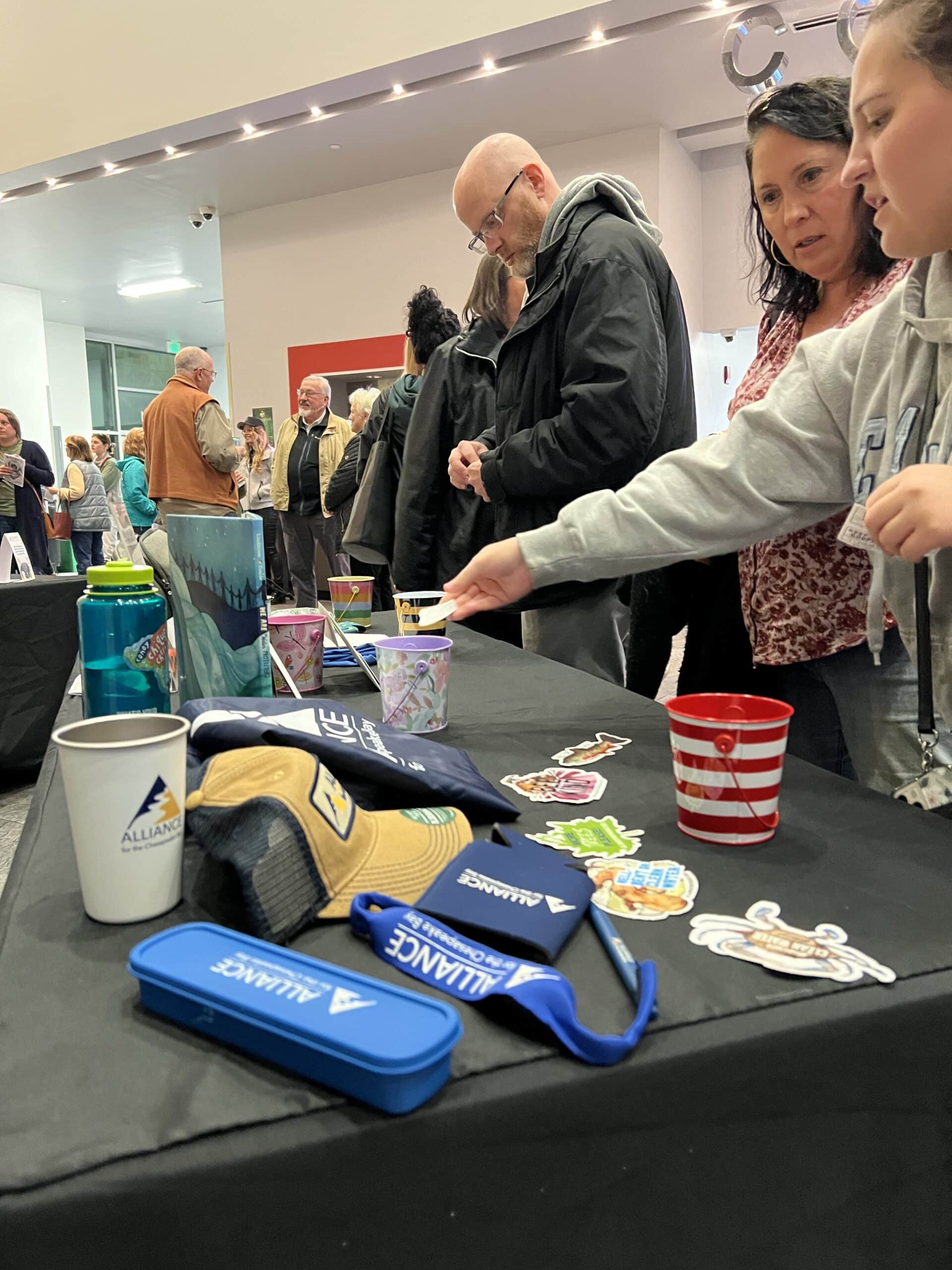 People looking at Alliance hats, cups, and stickers