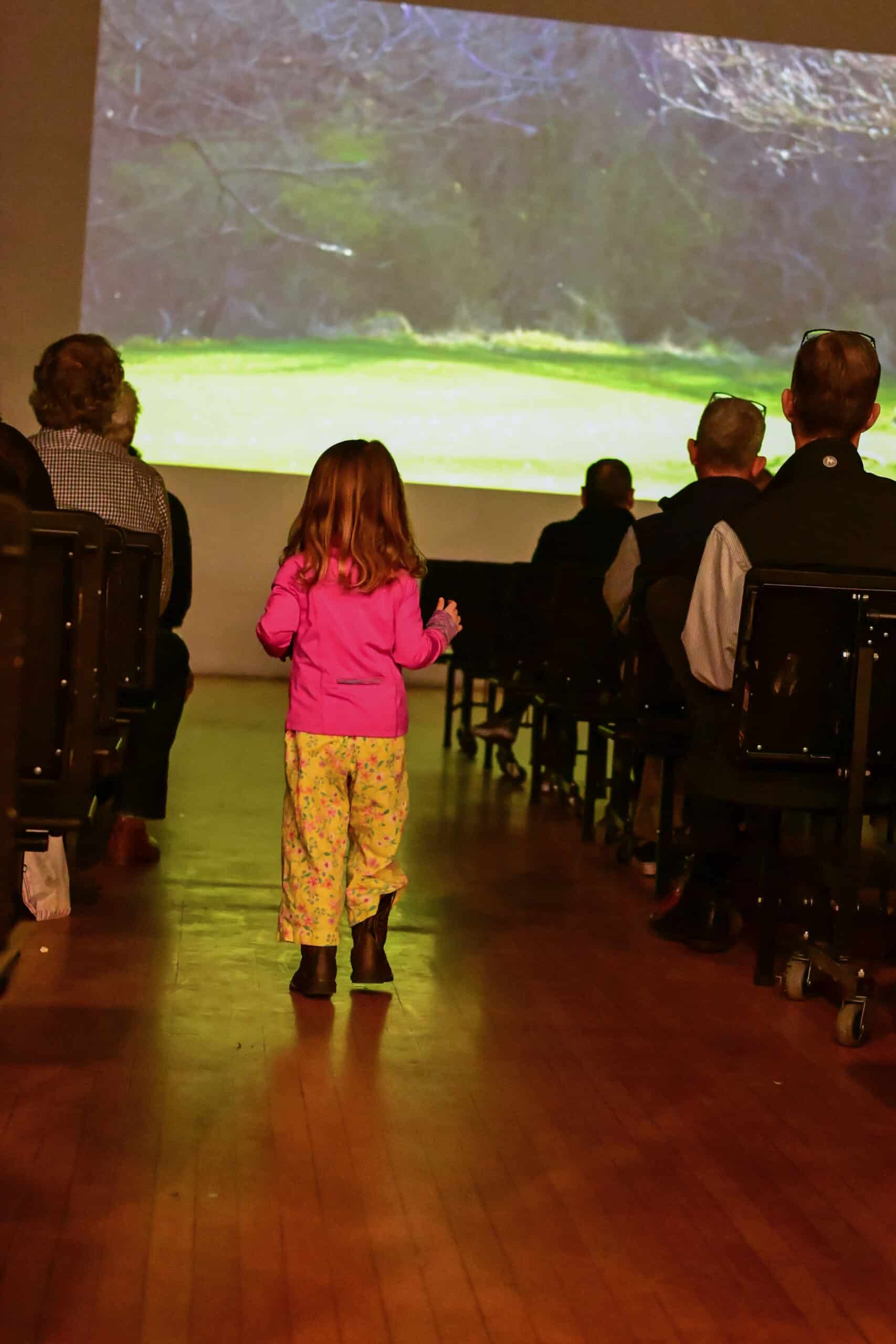 A child walking down the aisle of a movie theater