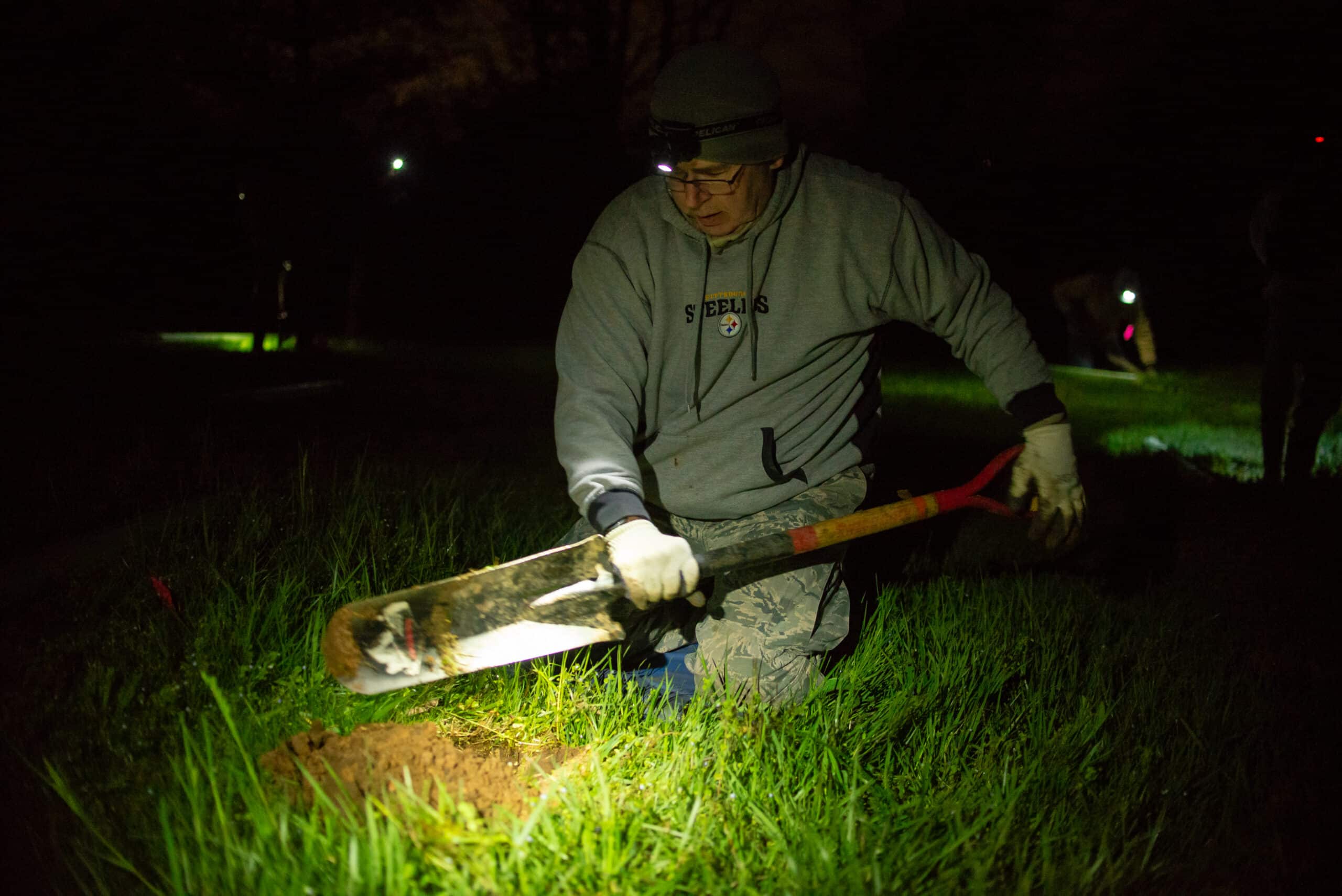 A person digging a hole, preparing to plant a tree seedling