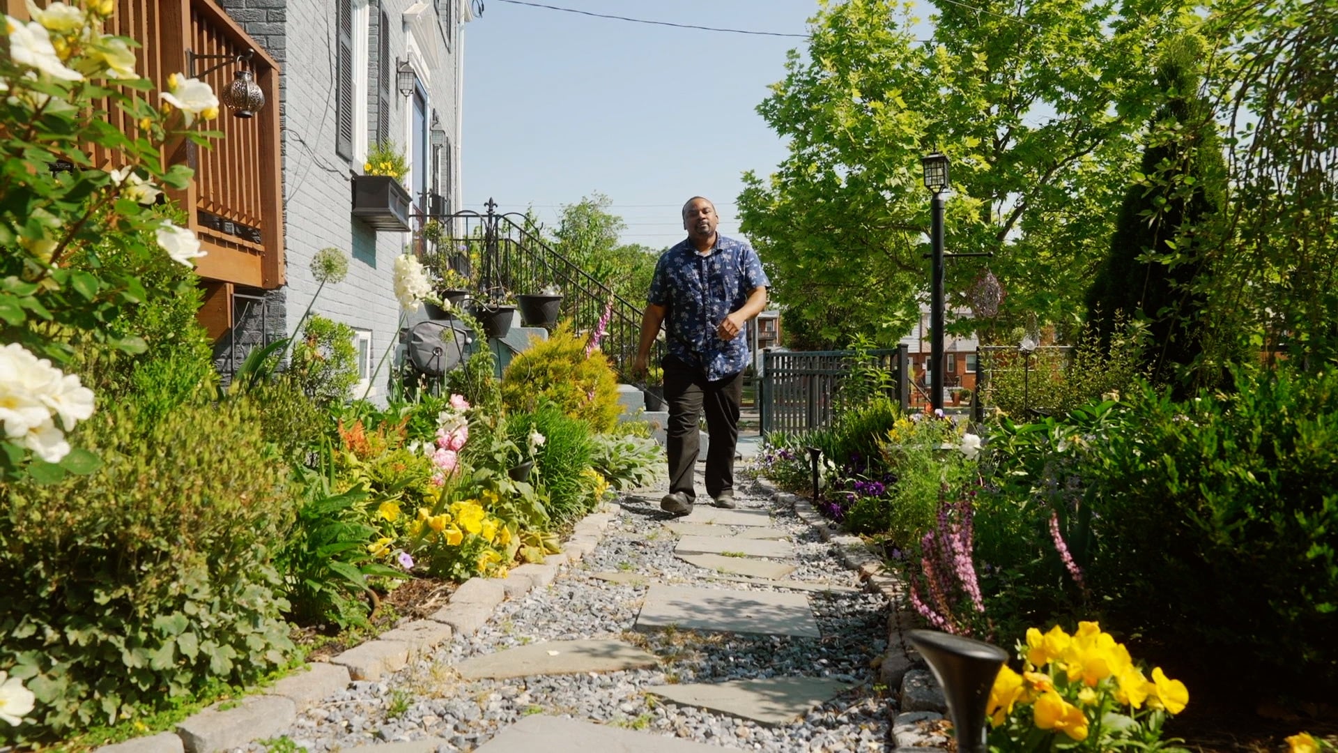 A person walking through a garden of flowers, shrubs, and other various plants