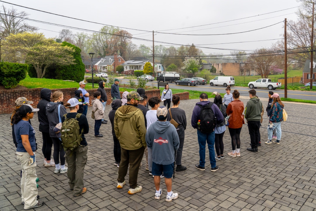 a group of people gathered around a speaker in a permeable parking lot