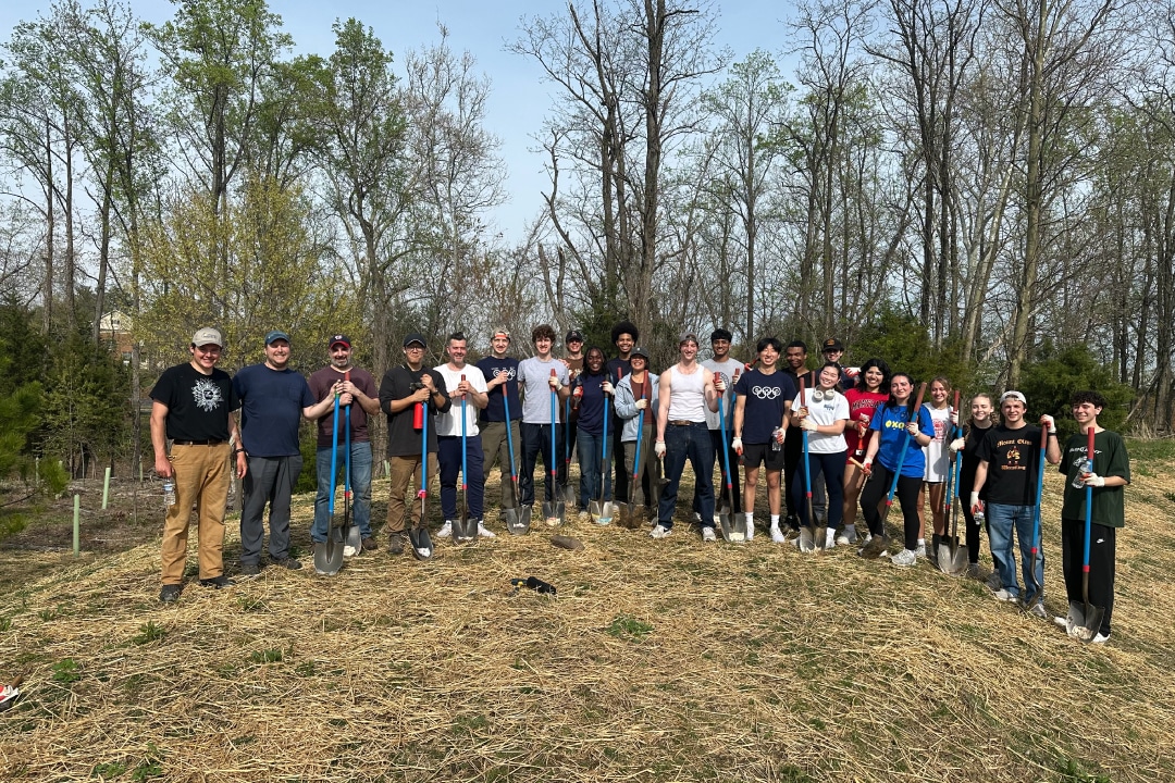 a group of people pose for a group picture in front of a treeline