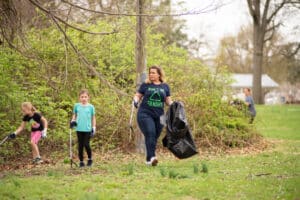 Children and adults clean up trash with grabbers