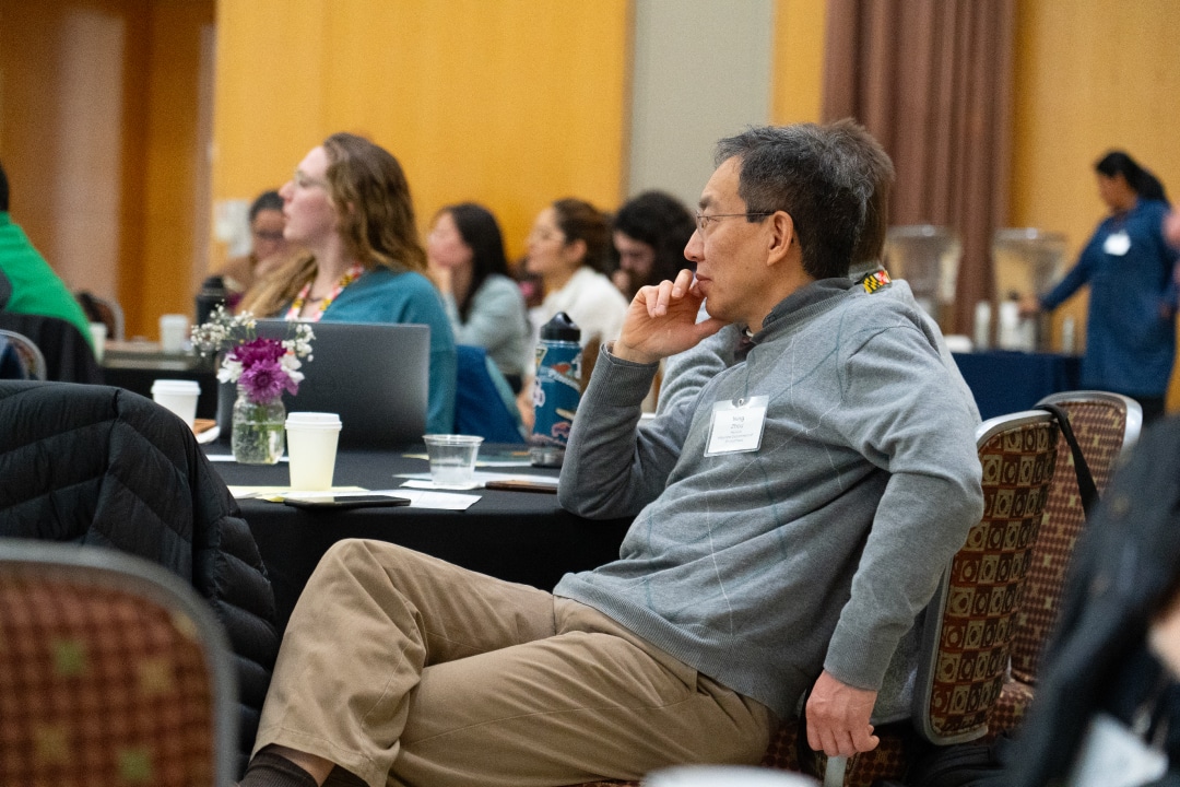 a person listens intently to a speaker while sitting at a roundtable