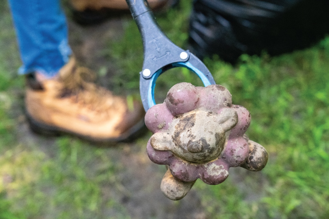 a close up of a dog toy held by a trash grabber