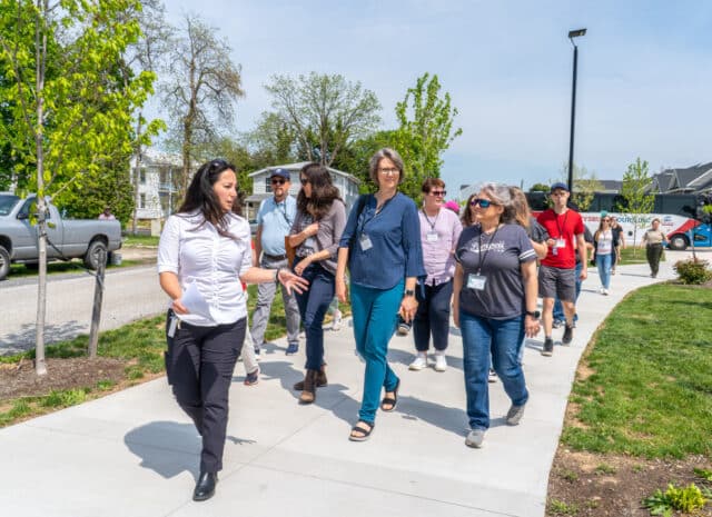 A person speaks to a group of people while leading them down a sidewalk