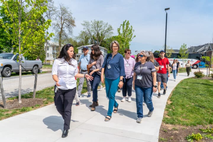 A person speaks to a group of people while leading them down a sidewalk