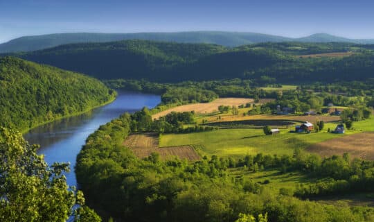 an aerial view of a farm next to a large river