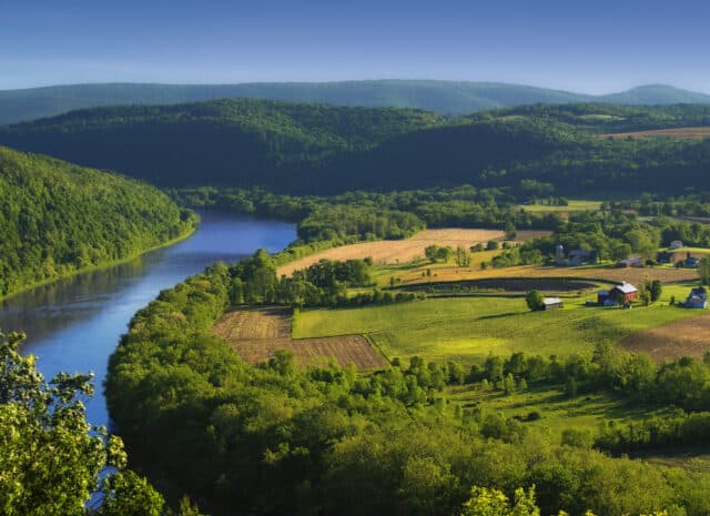 an aerial view of a farm next to a large river