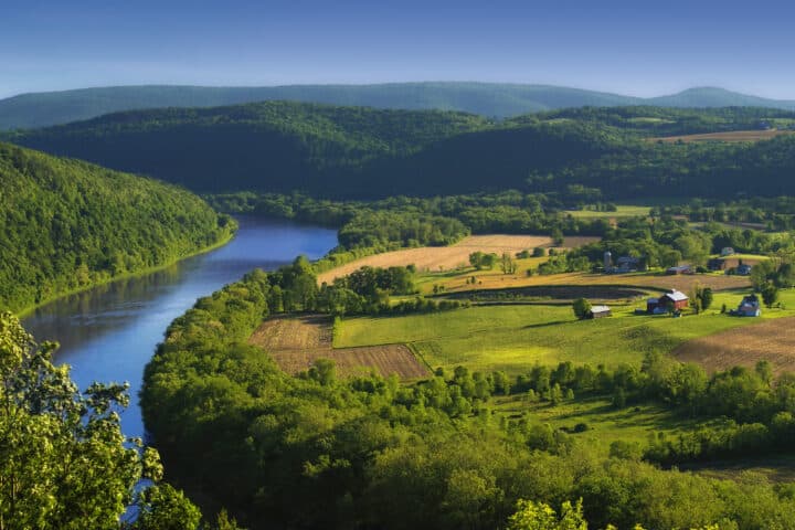 an aerial view of a farm next to a large river