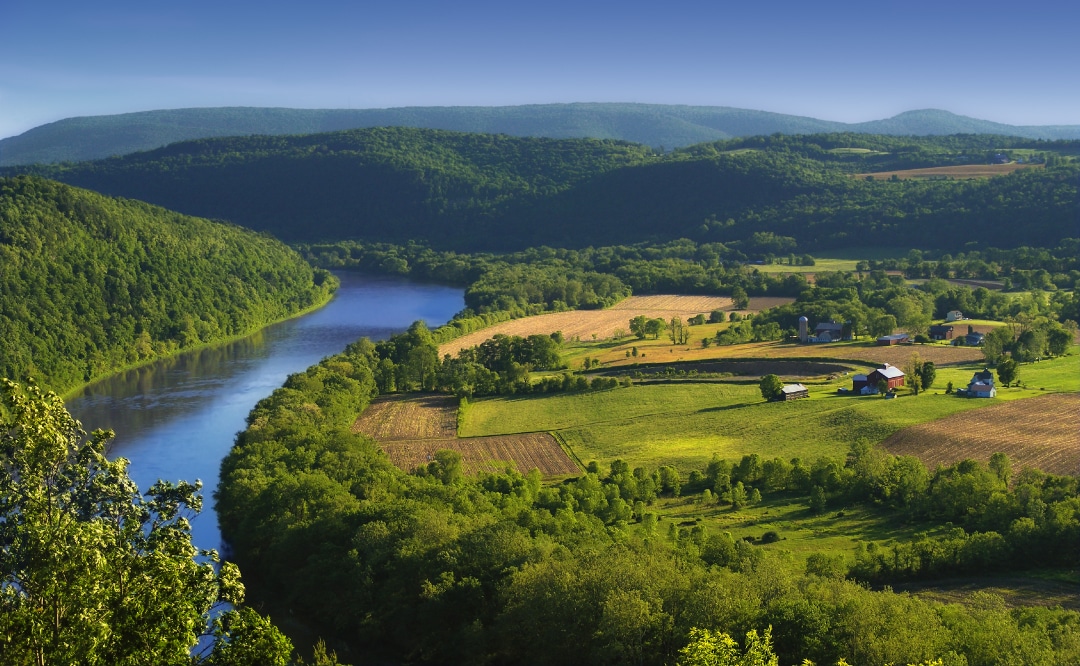 an aerial view of a farm next to a large river