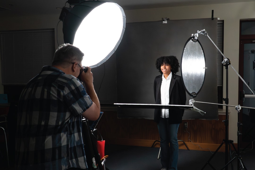 a person smiles while a photographer takes a headshot