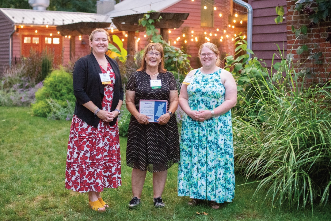 three people pose for a picture while the middle person holds an award plaque