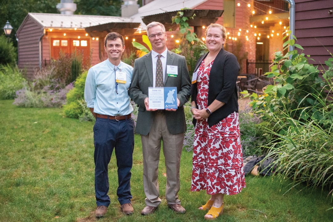 three people pose for a picture while the middle person holds an award plaque