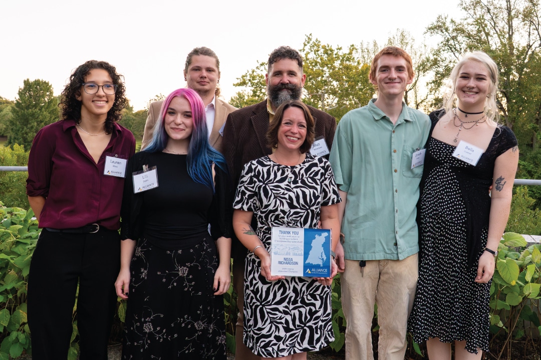 a group of people pose for a picture with the middle person holding an award plaque