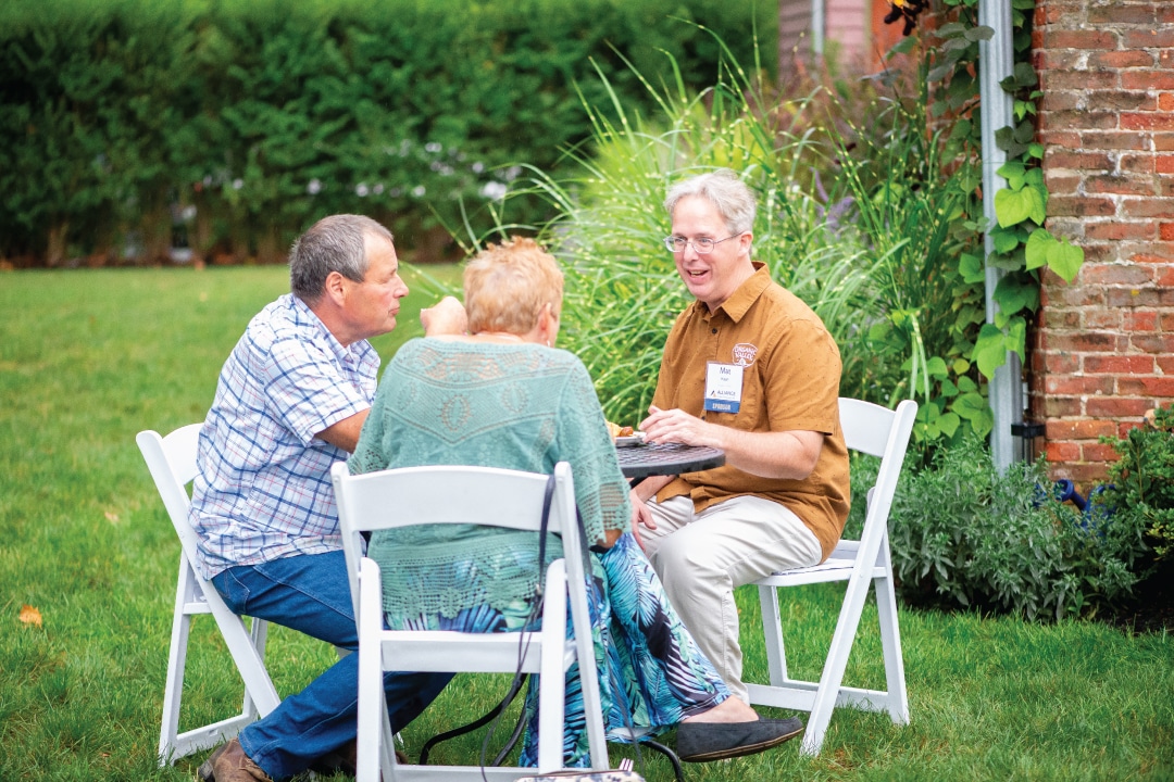 people talk while sitting at a small table outdoors