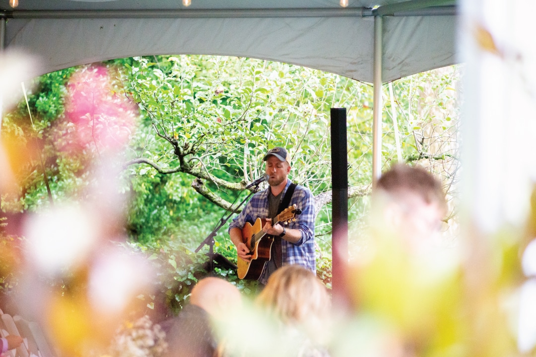 a person play guitar and sings under a canopy tent
