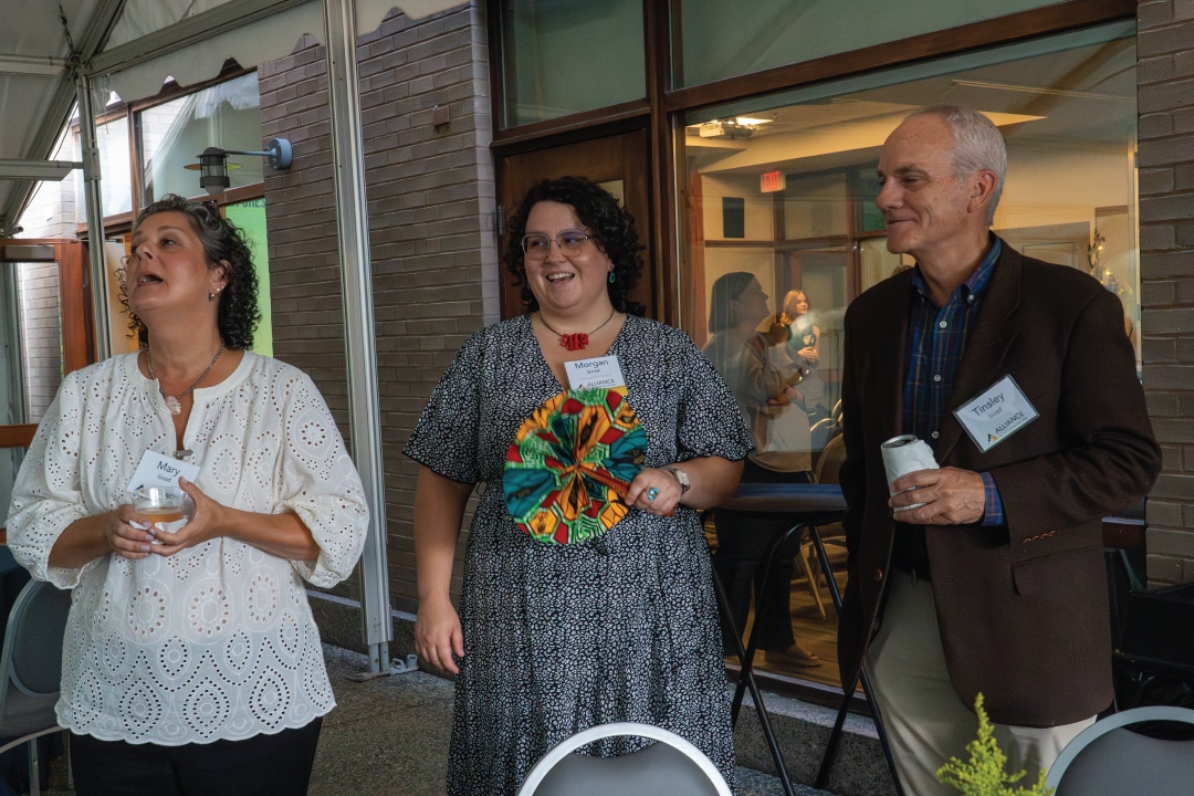 three people smiling and talk on a patio