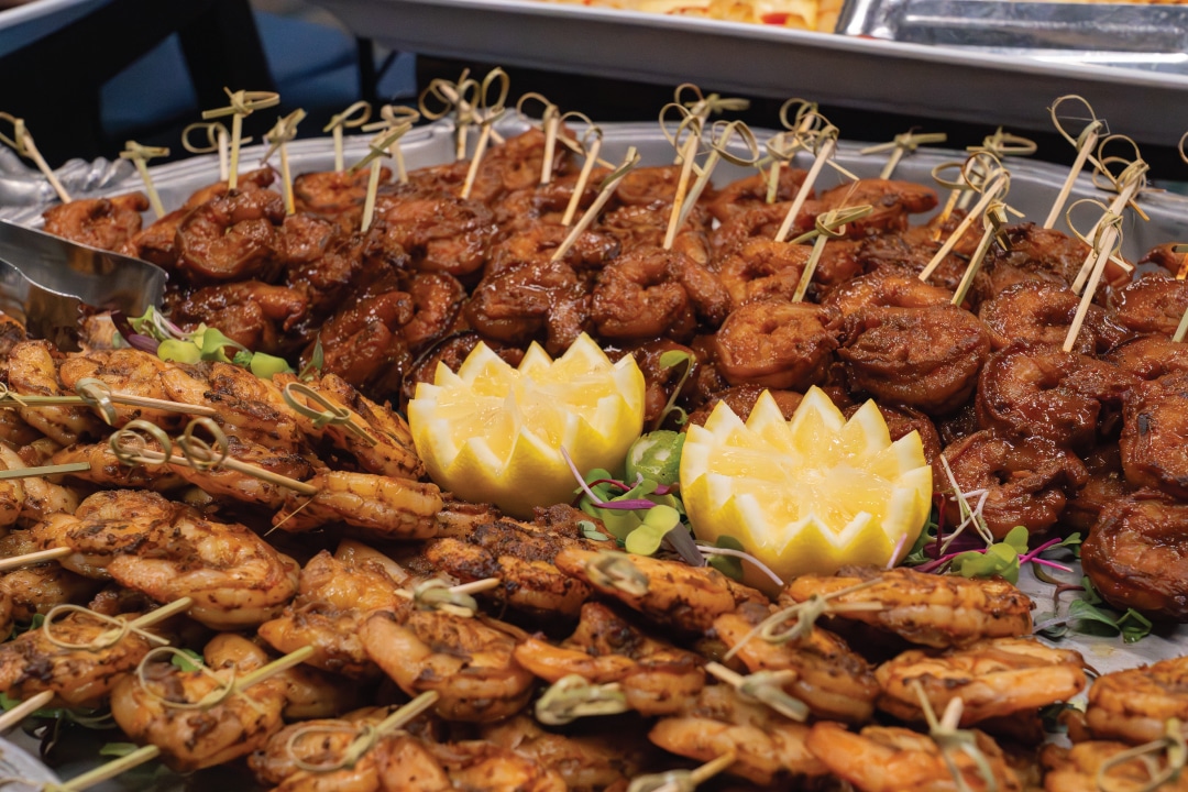 shrimp skewers on a plate with lemon garnish