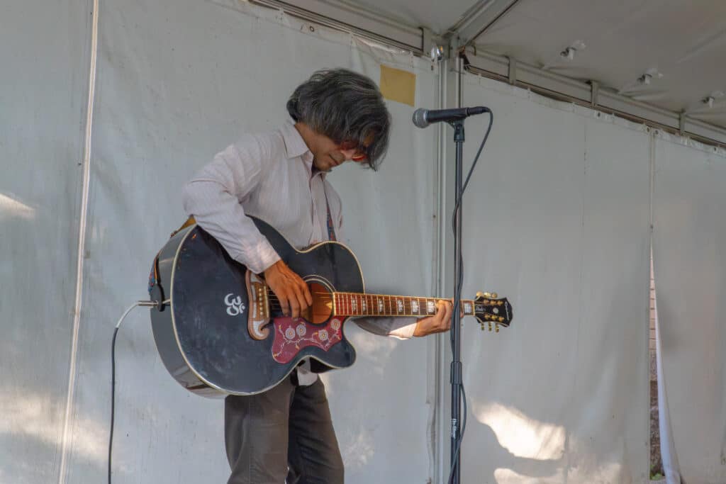a person playing a black guitar under a canopy tent
