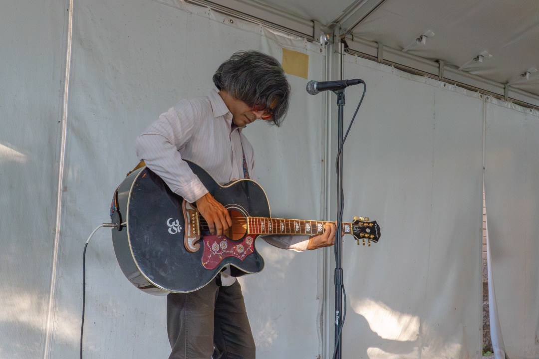 a person playing a black guitar under a canopy tent