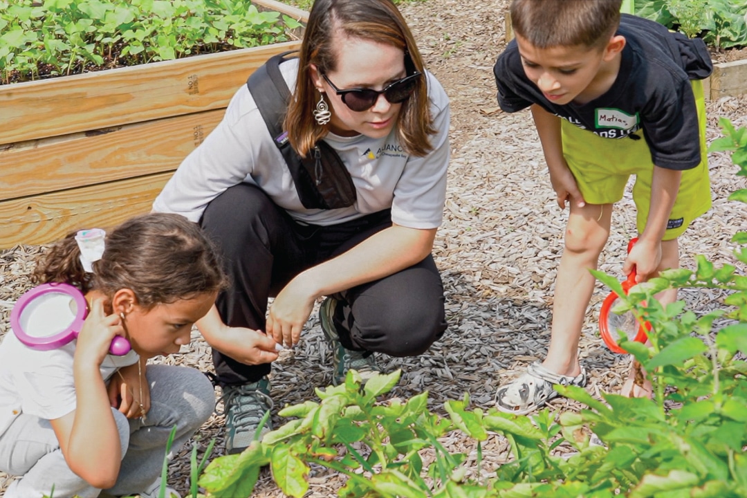two children examine plants in a garden