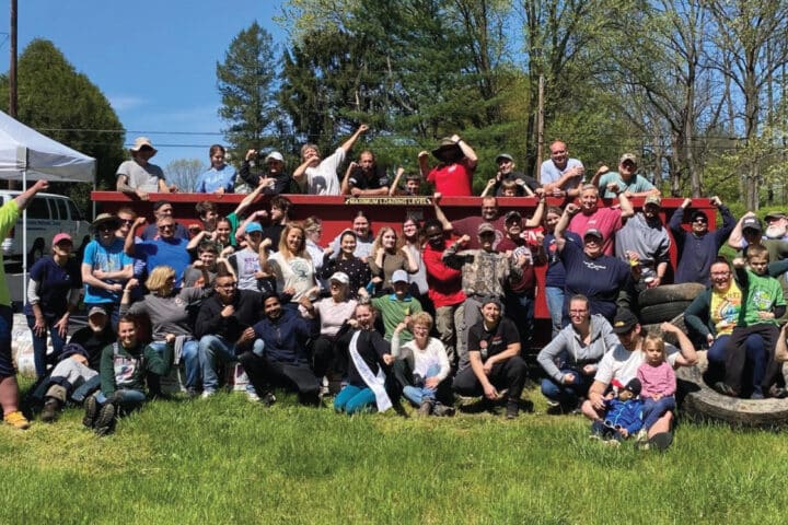 a large group of people flex their arms in celebration during a clean up event