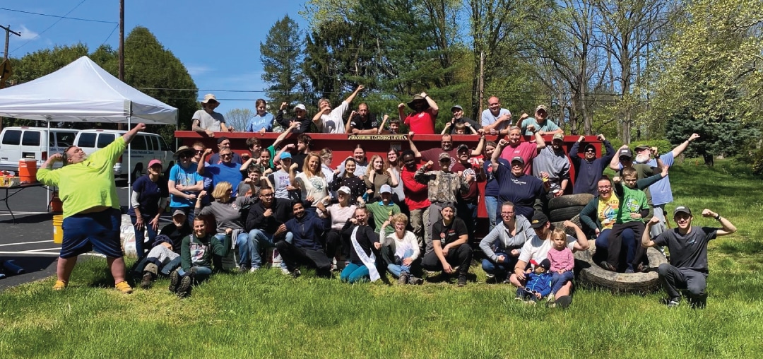 a large group of people flex their arms in celebration during a clean up event